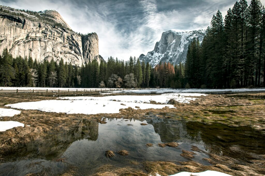 Serene winter landscape in Yosemite, showcasing snow-covered meadows and majestic cliffs.