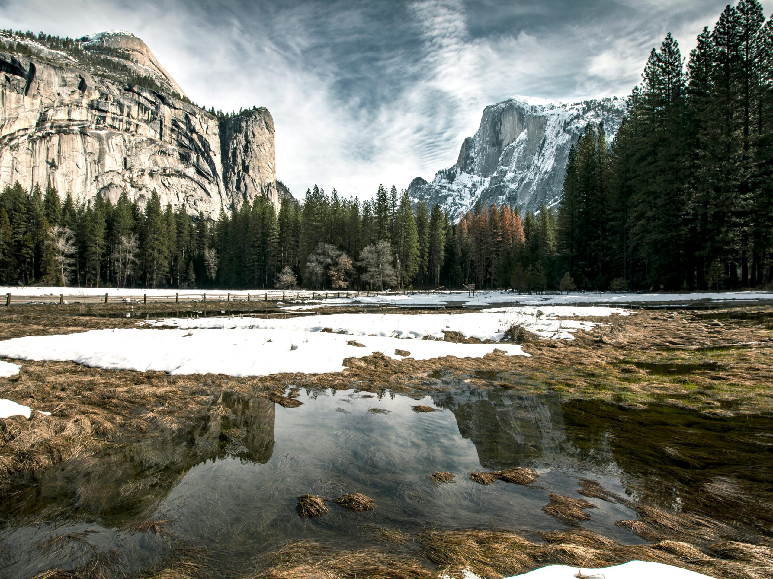 Serene winter landscape in Yosemite, showcasing snow-covered meadows and majestic cliffs.