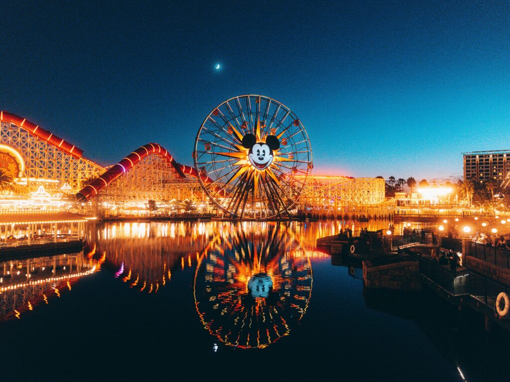 Stunning night view of Disneyland's Pixar Pier with Mickey Mouse Ferris wheel and reflected lights.
